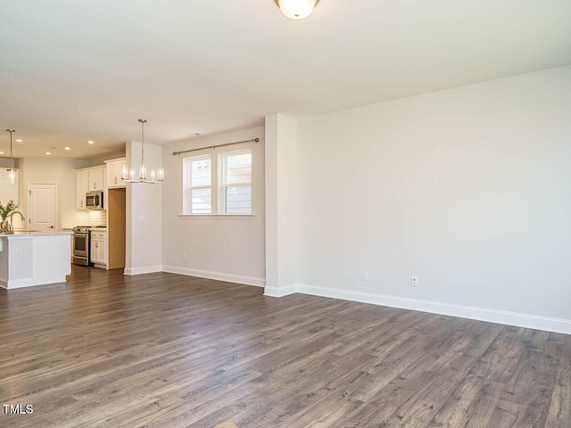 unfurnished living room featuring a sink, baseboards, an inviting chandelier, recessed lighting, and dark wood-type flooring