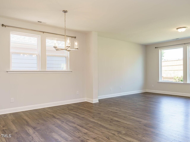 empty room featuring baseboards, a notable chandelier, visible vents, and dark wood-type flooring