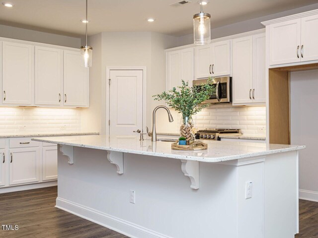 kitchen with white cabinets, stainless steel microwave, a sink, and range