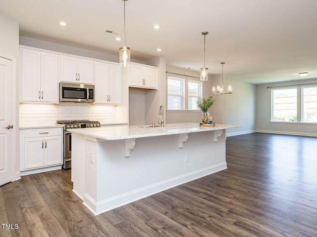 kitchen featuring a large island, dark wood-style floors, white cabinets, a sink, and appliances with stainless steel finishes