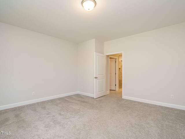 spare room with baseboards and light carpet