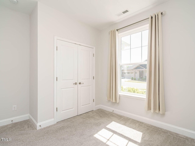 unfurnished bedroom featuring visible vents, carpet flooring, and multiple windows