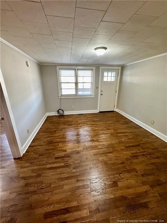 foyer entrance featuring crown molding, wood finished floors, and baseboards