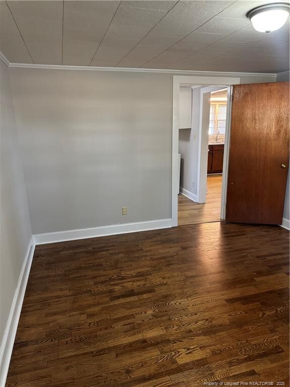 unfurnished room featuring dark wood-style floors, a sink, and baseboards
