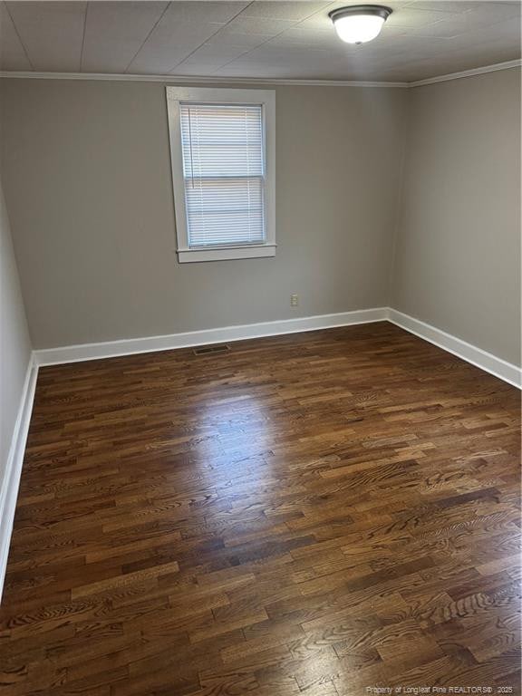 unfurnished room with crown molding, baseboards, and dark wood-type flooring