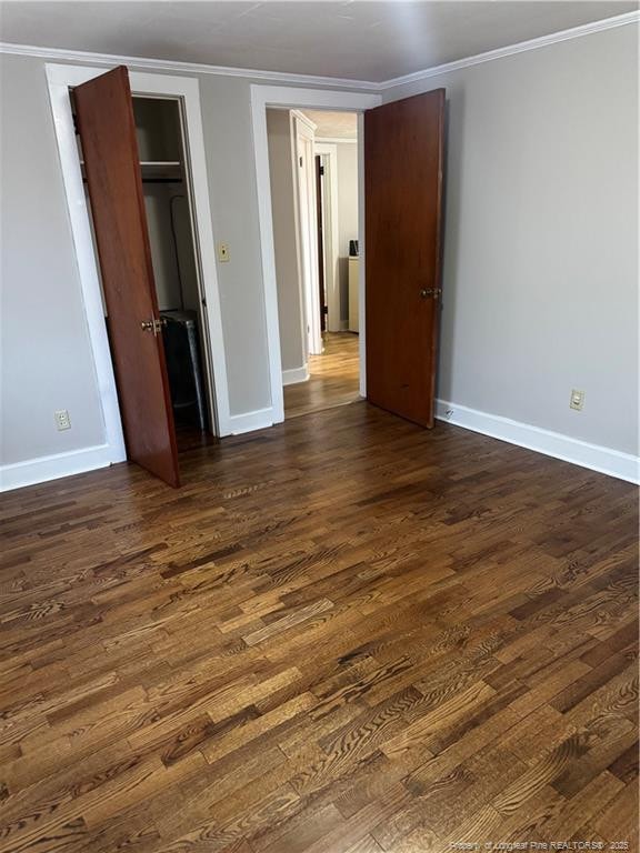 unfurnished bedroom featuring dark wood-type flooring, ornamental molding, and baseboards