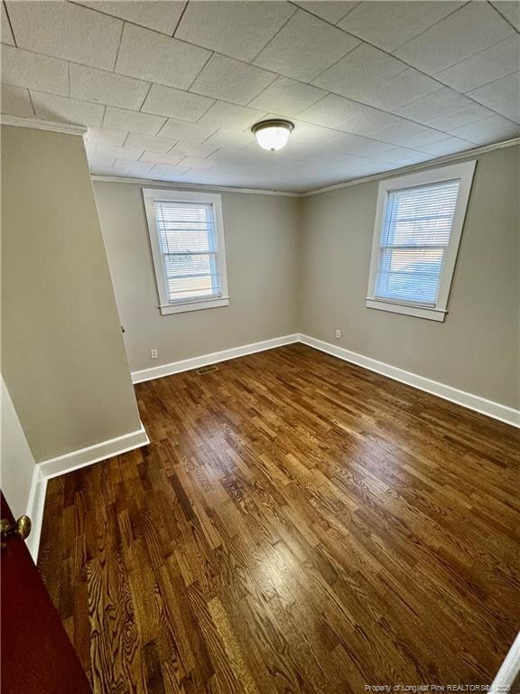 unfurnished room featuring wood finished floors, ornamental molding, and baseboards