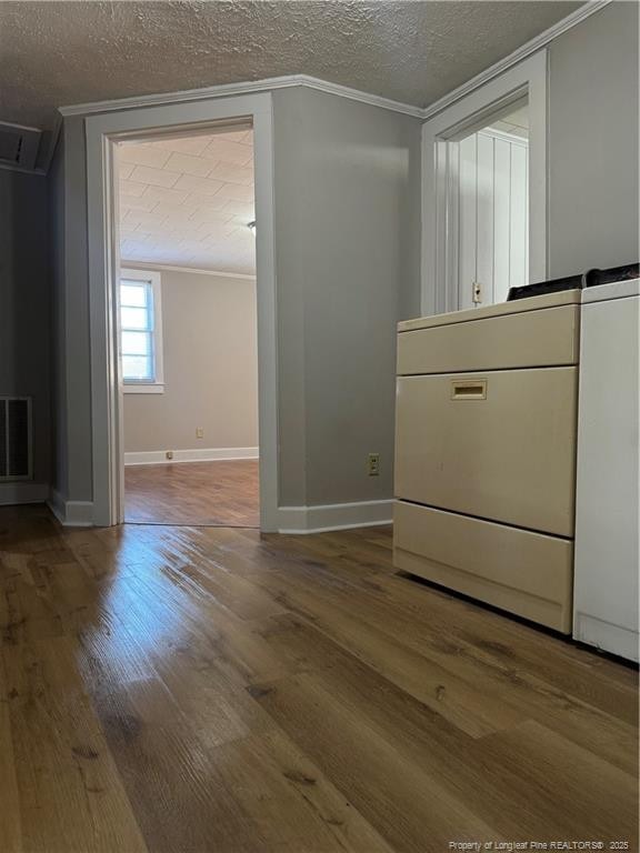 interior space featuring crown molding, a textured ceiling, visible vents, and wood finished floors