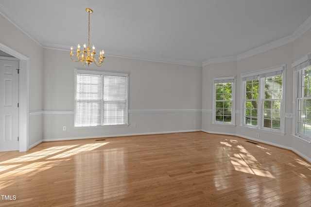 spare room featuring an inviting chandelier, baseboards, plenty of natural light, and hardwood / wood-style flooring
