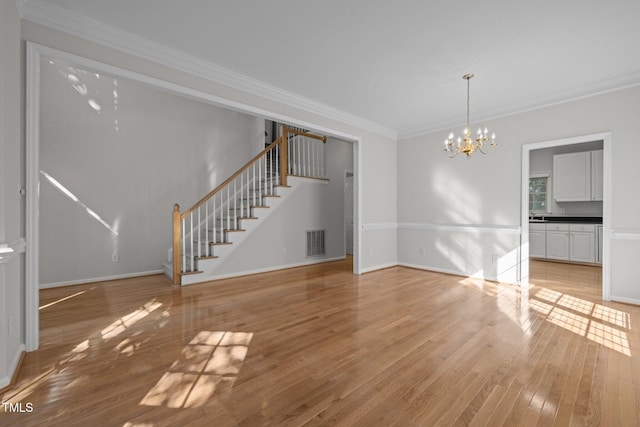 interior space with crown molding, a notable chandelier, light wood-type flooring, visible vents, and stairway