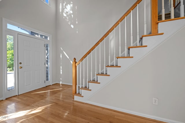 foyer featuring stairs, a high ceiling, baseboards, and wood finished floors