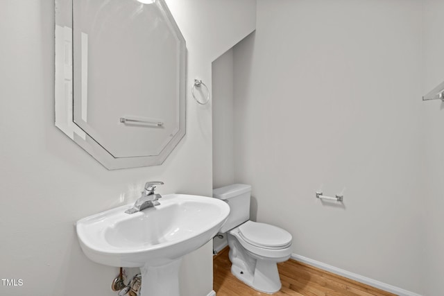 bathroom featuring a sink, baseboards, toilet, and wood finished floors