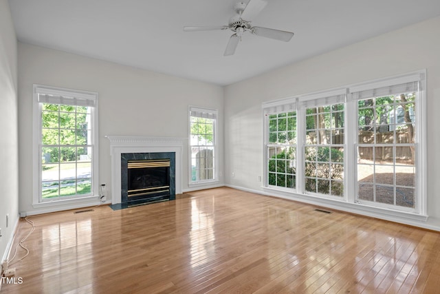 unfurnished living room with a ceiling fan, visible vents, baseboards, wood-type flooring, and a premium fireplace