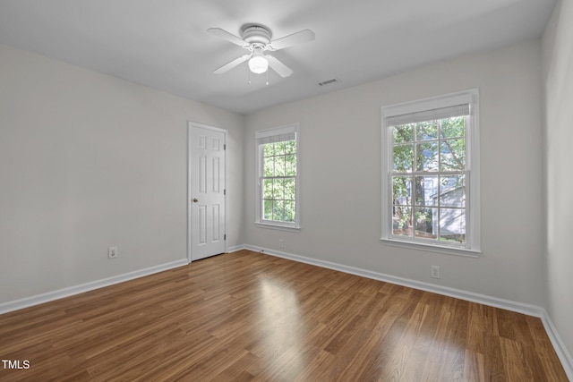 empty room with baseboards, visible vents, ceiling fan, and wood finished floors