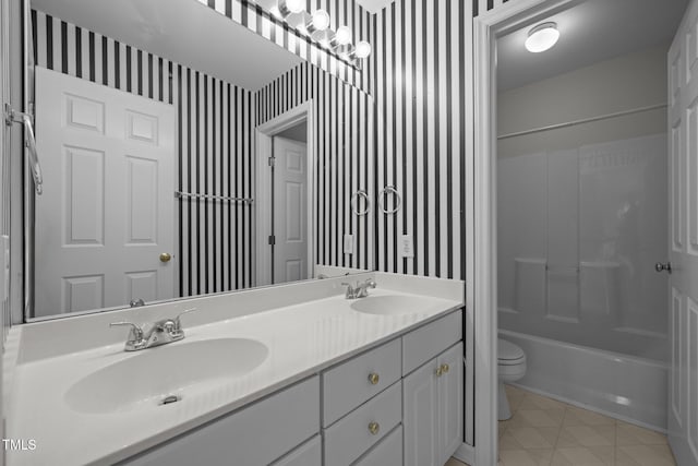 bathroom featuring a sink, toilet, wallpapered walls, and double vanity