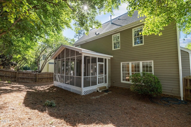 back of property featuring roof with shingles, fence, and a sunroom