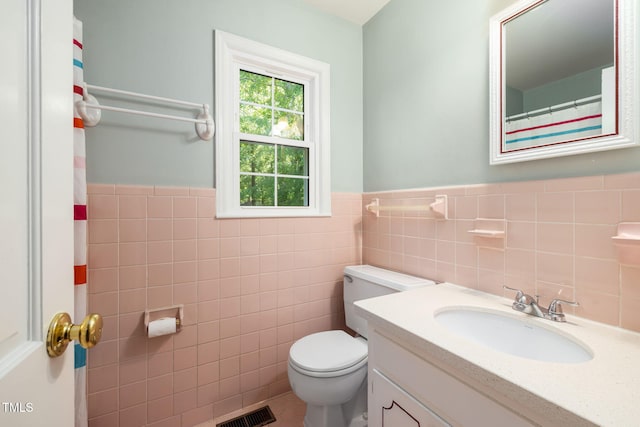 bathroom featuring visible vents, tile walls, a wainscoted wall, vanity, and toilet