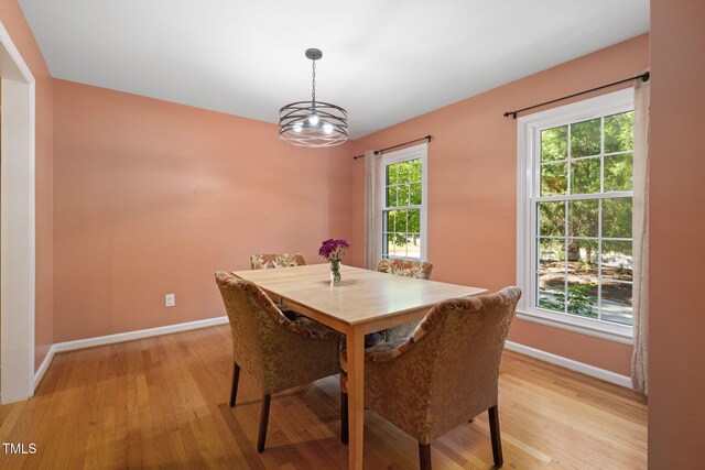 dining room with baseboards, a notable chandelier, and light wood-style floors