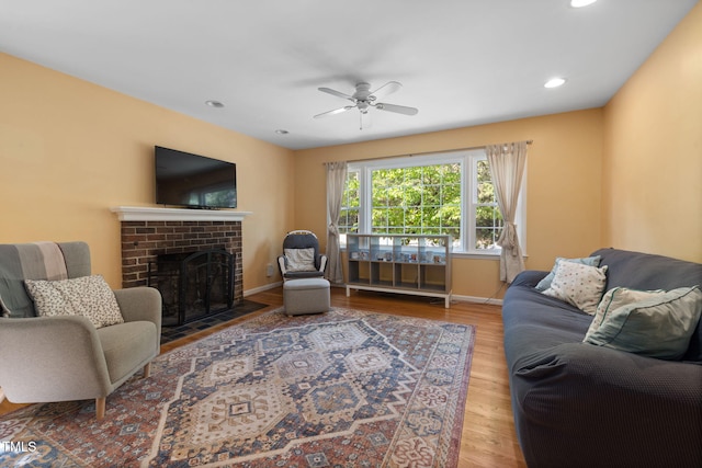 living area with a ceiling fan, a fireplace, wood finished floors, baseboards, and recessed lighting