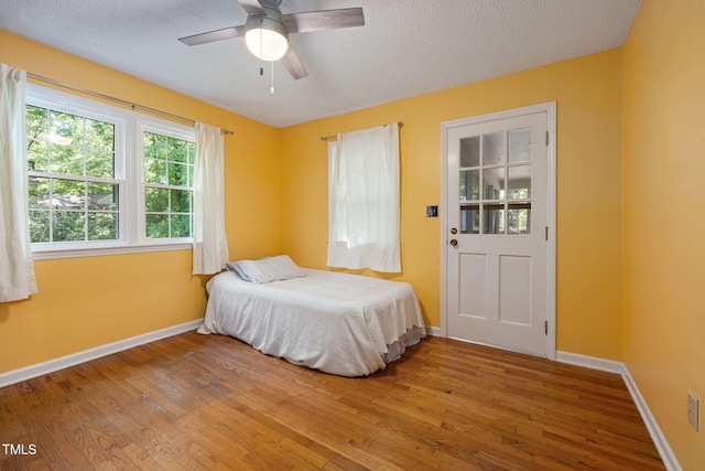 bedroom with baseboards, a textured ceiling, light wood finished floors, and a ceiling fan