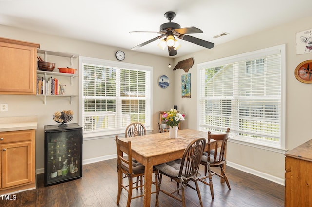 dining room featuring dark wood-type flooring, a ceiling fan, visible vents, and baseboards
