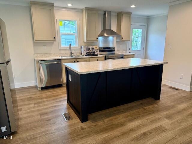 kitchen featuring a sink, visible vents, stainless steel appliances, ornamental molding, and wall chimney exhaust hood