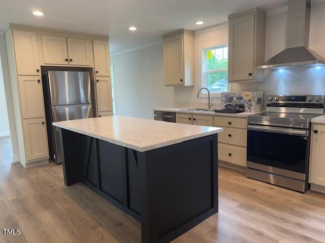 kitchen with light wood-style flooring, appliances with stainless steel finishes, wall chimney range hood, a sink, and crown molding