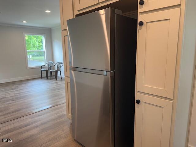 kitchen with ornamental molding, baseboards, freestanding refrigerator, and light wood-type flooring