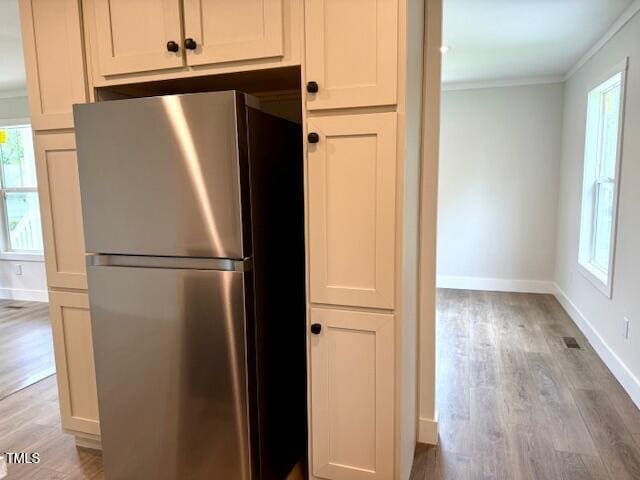 kitchen with a healthy amount of sunlight, crown molding, light wood finished floors, and freestanding refrigerator