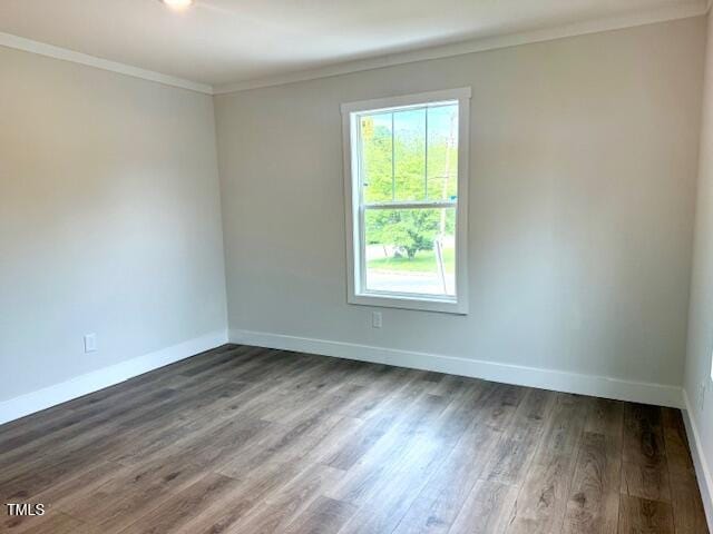 spare room featuring crown molding, wood finished floors, and baseboards