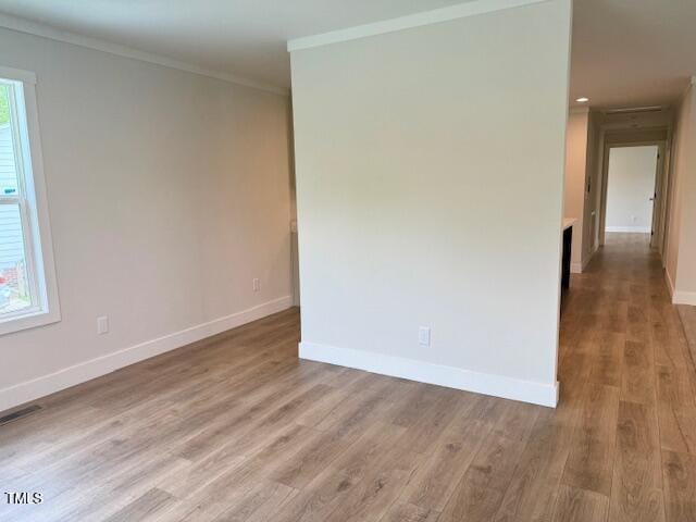 unfurnished room with baseboards, visible vents, wood finished floors, and ornamental molding