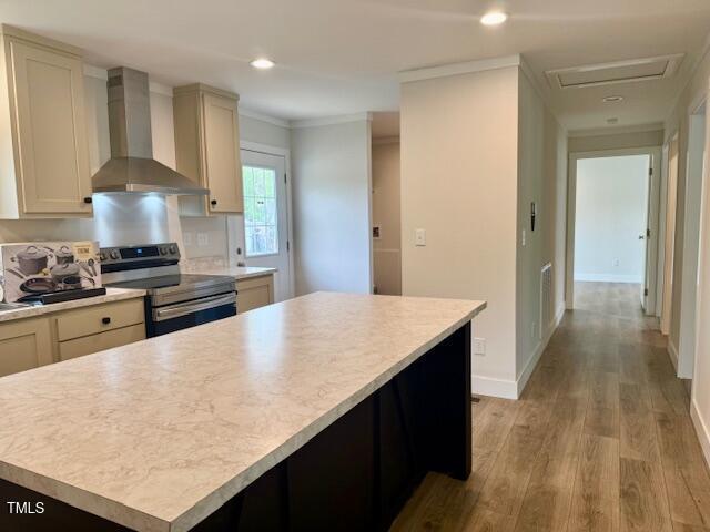 kitchen featuring light countertops, stainless steel electric range, light wood finished floors, a center island, and wall chimney exhaust hood