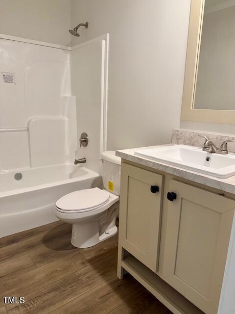 bathroom featuring toilet, vanity, shower / washtub combination, and wood finished floors