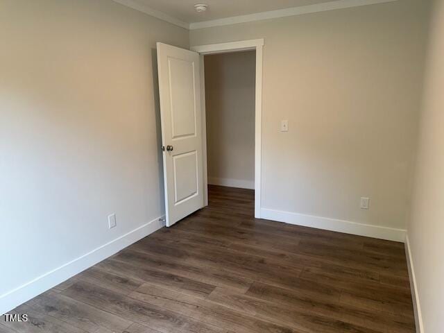 unfurnished room with ornamental molding, dark wood-style floors, and baseboards