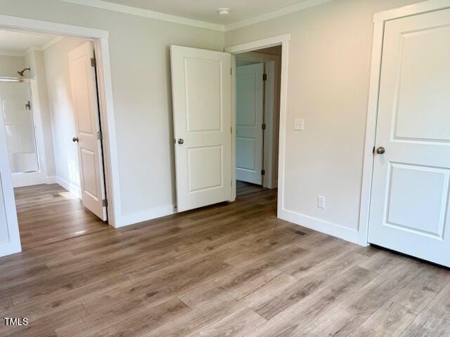 unfurnished bedroom featuring baseboards, light wood-type flooring, and crown molding