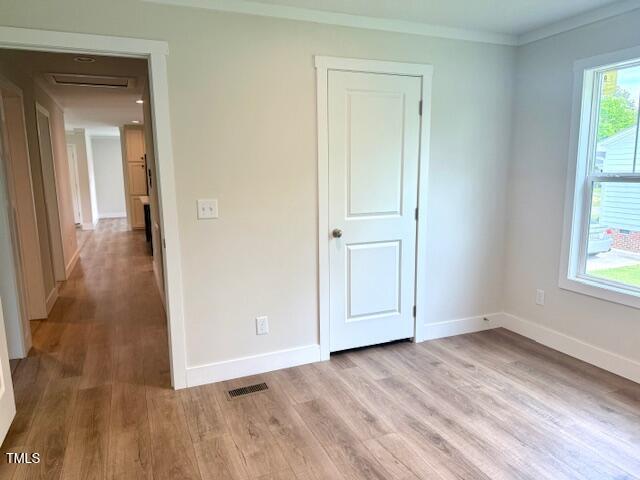 unfurnished bedroom featuring crown molding, visible vents, baseboards, and light wood-style floors