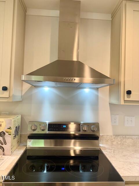 kitchen with electric stove, white cabinets, wall chimney exhaust hood, and light countertops