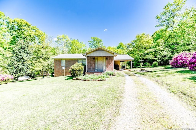 ranch-style house featuring brick siding, a carport, driveway, and a front yard