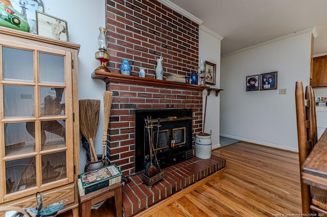living room with crown molding, a brick fireplace, wood finished floors, and baseboards