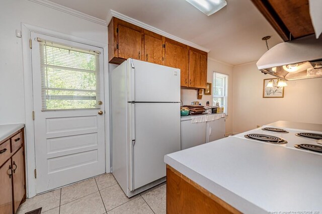 kitchen with brown cabinetry, ornamental molding, light tile patterned flooring, and freestanding refrigerator