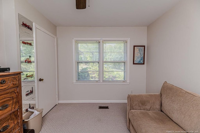 living area featuring baseboards, visible vents, a ceiling fan, and light carpet