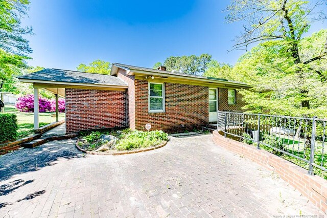 view of front facade with brick siding, fence, and a patio area