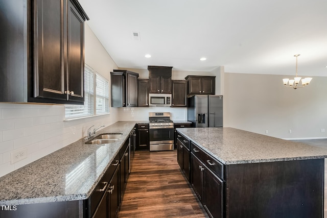 kitchen featuring dark brown cabinetry, a center island, a chandelier, a sink, and appliances with stainless steel finishes