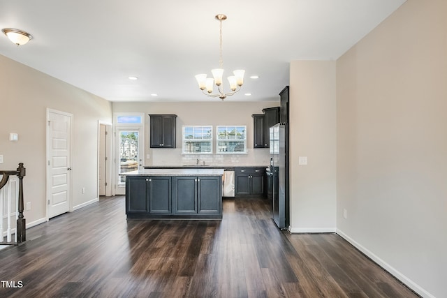 kitchen featuring dark wood-style flooring, a sink, light countertops, a chandelier, and baseboards