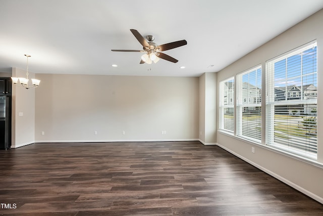 empty room with recessed lighting, baseboards, ceiling fan with notable chandelier, and dark wood-style flooring
