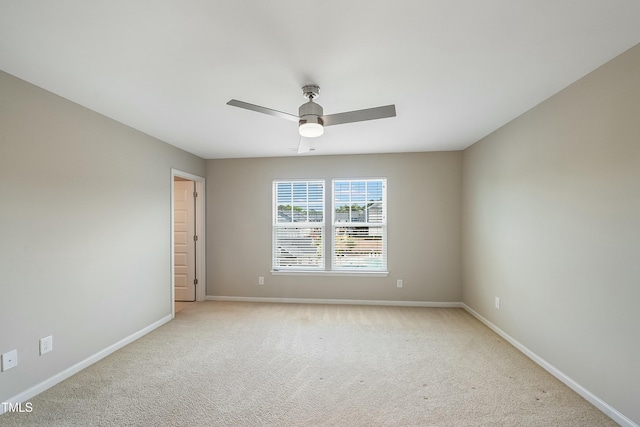 spare room with a ceiling fan, baseboards, and light colored carpet