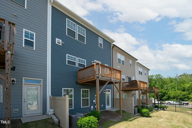 back of house featuring a lawn, fence, cooling unit, and a deck