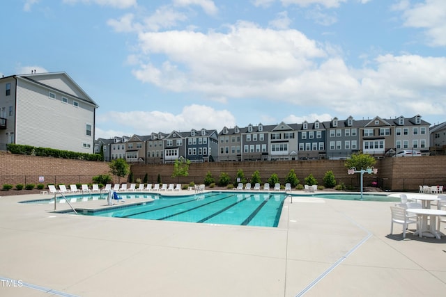 community pool with a residential view, fence, and a patio area