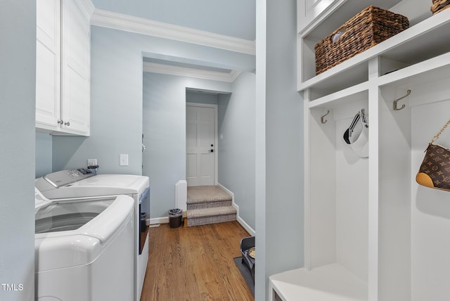 washroom featuring crown molding, cabinet space, washer and dryer, baseboards, and wood finished floors
