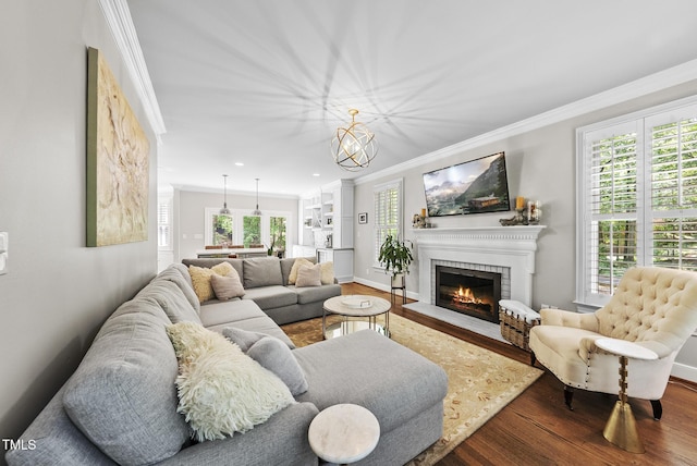 living area with ornamental molding, a brick fireplace, wood finished floors, and a wealth of natural light